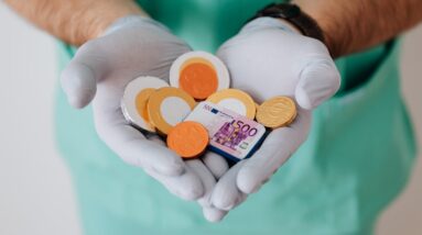 Faceless doctor with chocolate coins in hands